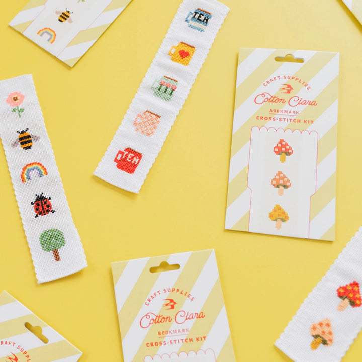 Cross-stitch kits with colorful designs on a yellow background