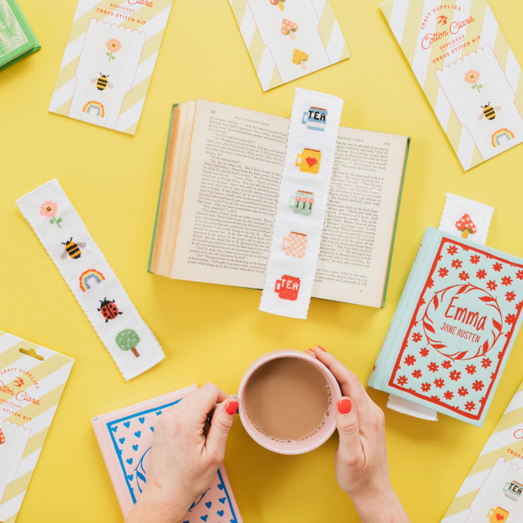 Open book with decorative bookmarks and a cup of tea on a yellow background