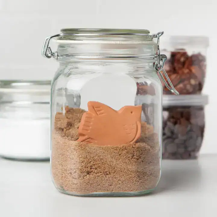 Glass jar with a fish-shaped sand toy on a white background