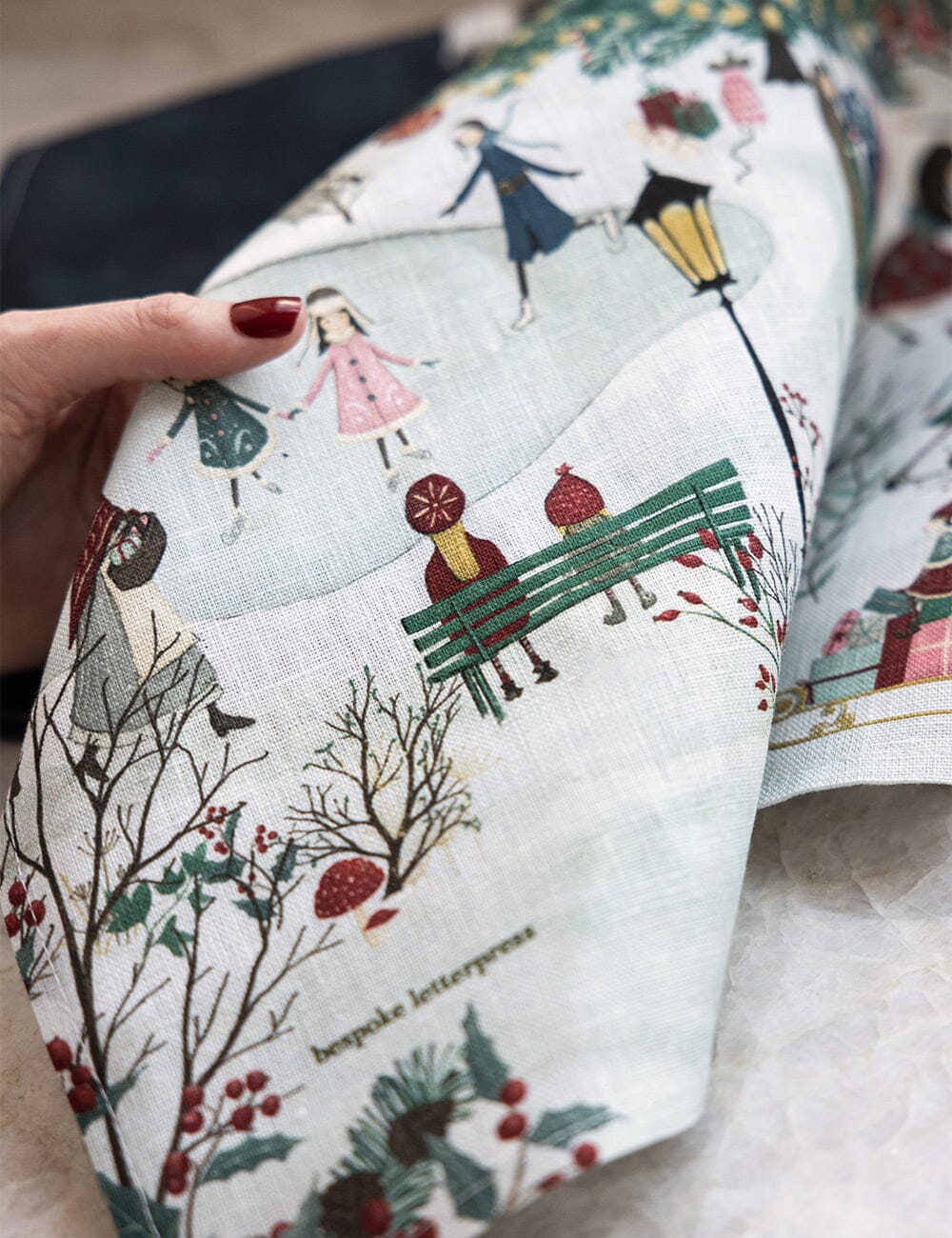 A close up of a christmas linen tea towel with a village theme 