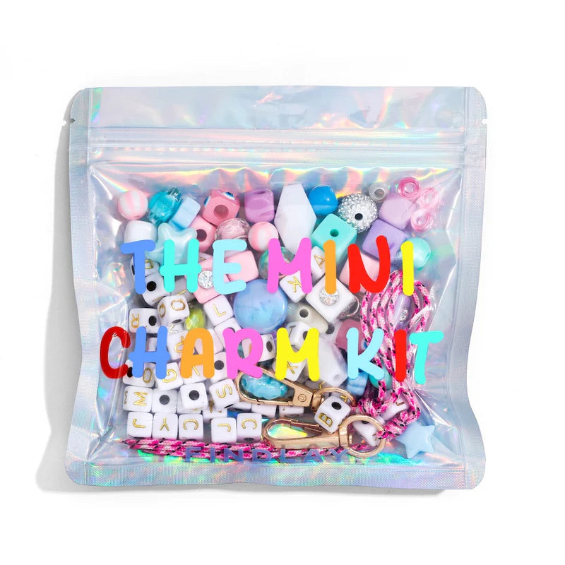 Mini charm kit with colorful charms in a clear bag on a white background