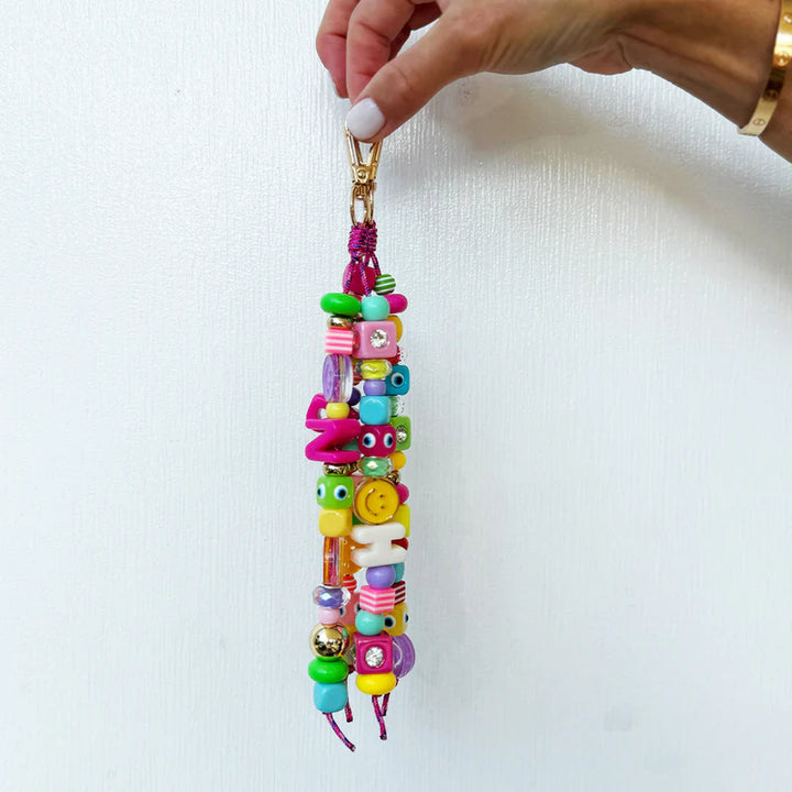 Colorful beaded keychain held by a hand against a white background