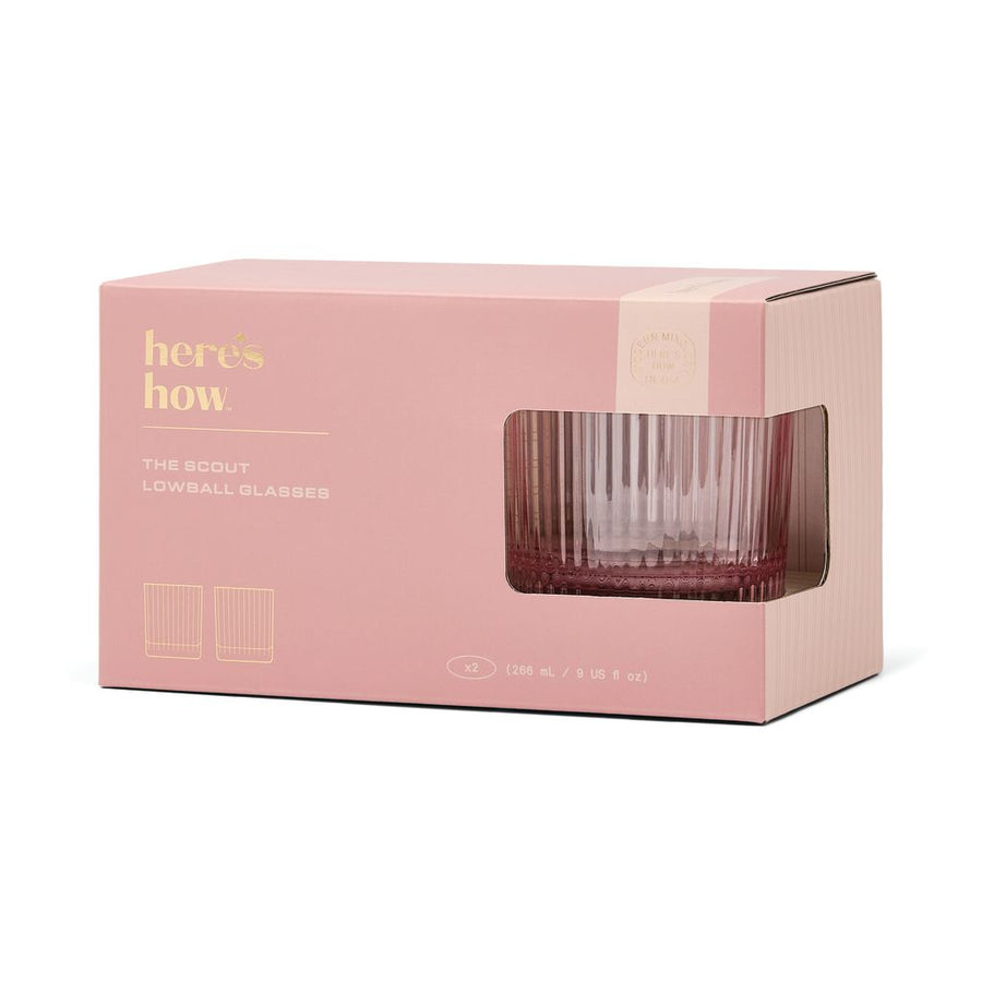 Pink packaging box with a clear window displaying a glass, featuring 'here's how' branding.