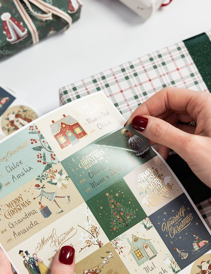 Hand holding a Christmas card with decorative designs and text.