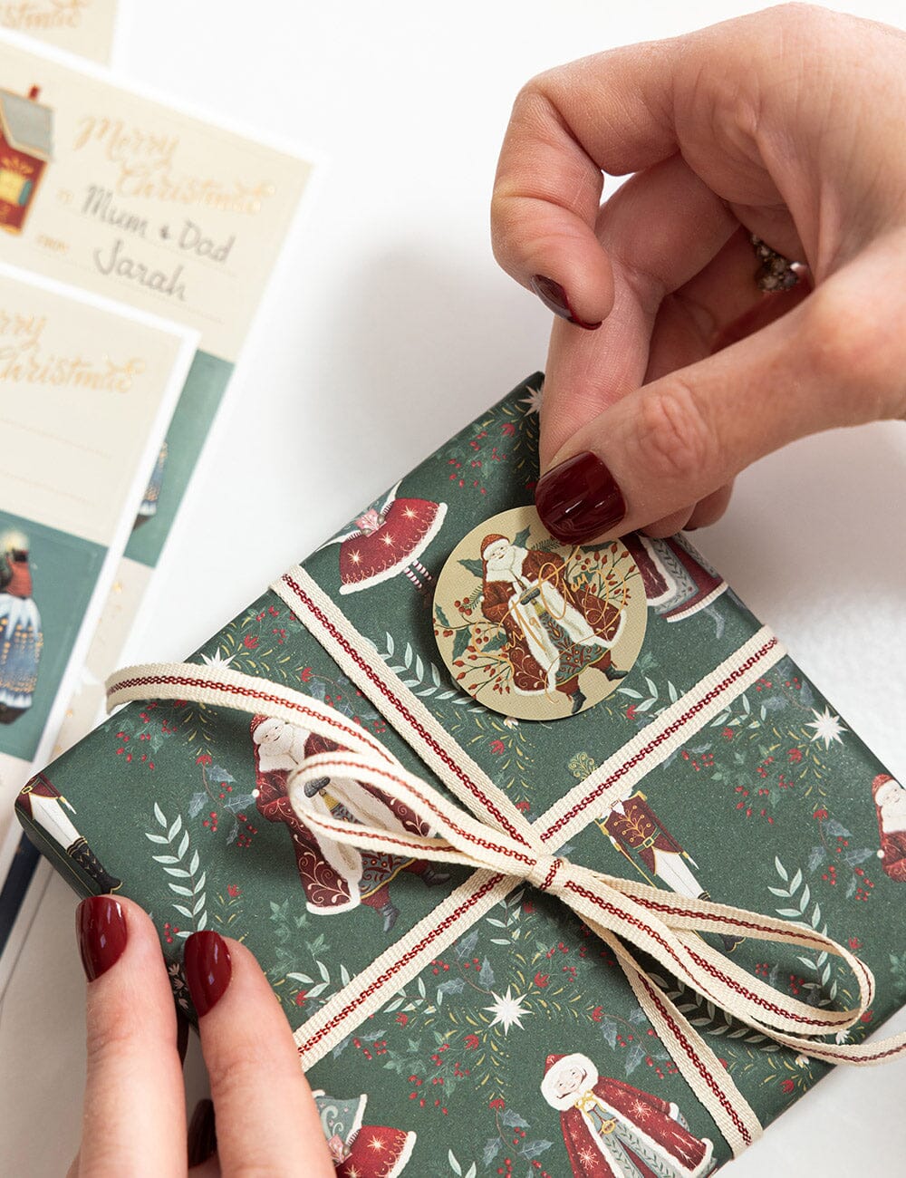 A hand sticking a sticker onto a christmas gift that is gift wrapped