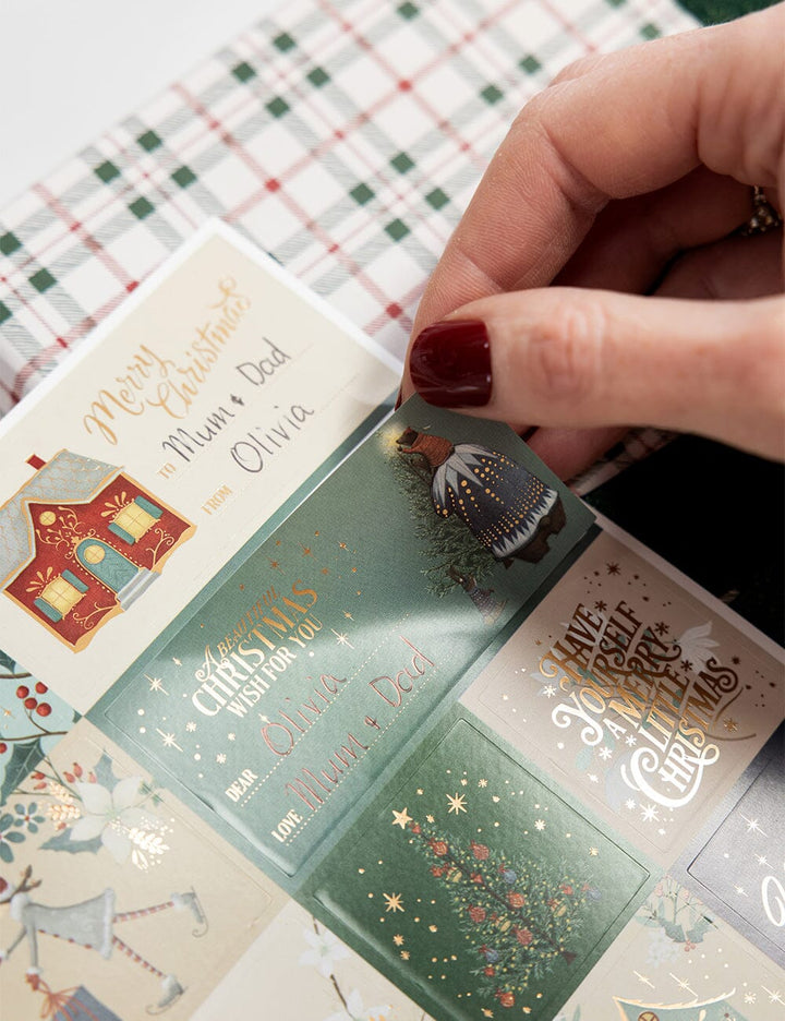 Hand holding a Christmas card with other cards in the background on a checkered tablecloth.