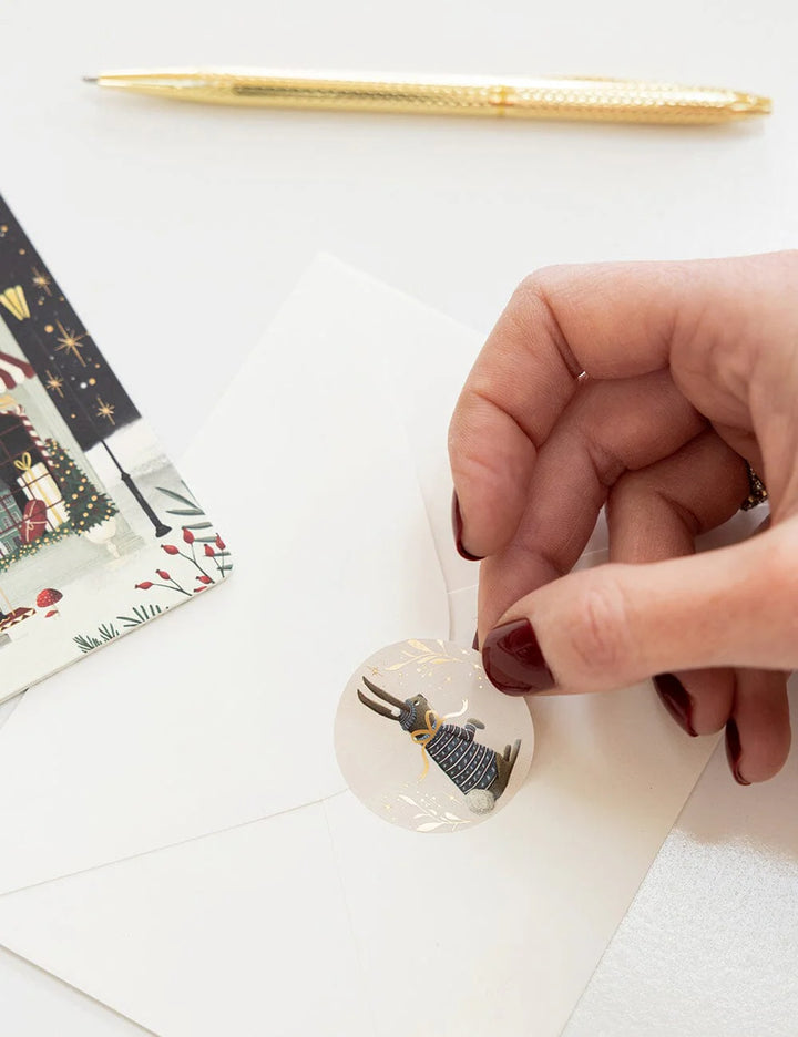 Hand holding a small decorative item on a white surface with a pen and paper in the background.