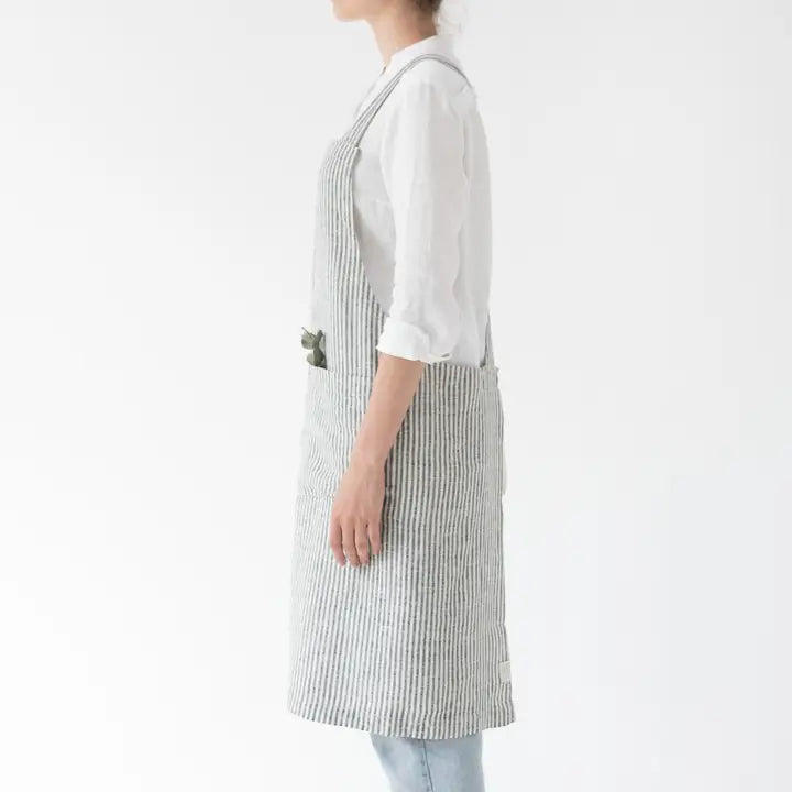 Person wearing a white shirt and striped apron on a plain background
