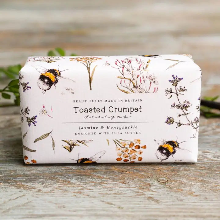 Bar of soap with floral and bee design packaging on a wooden surface