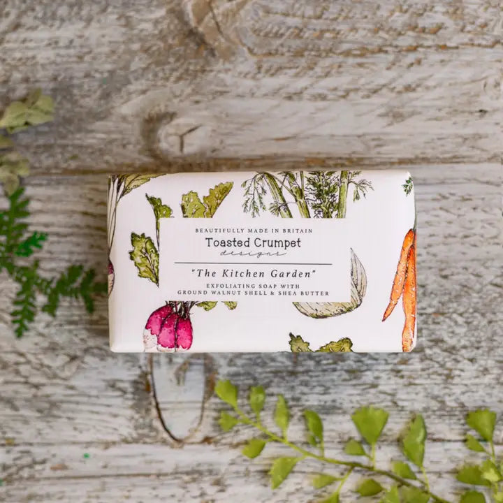 Bar of soap with a decorative label on a wooden surface with green leaves.