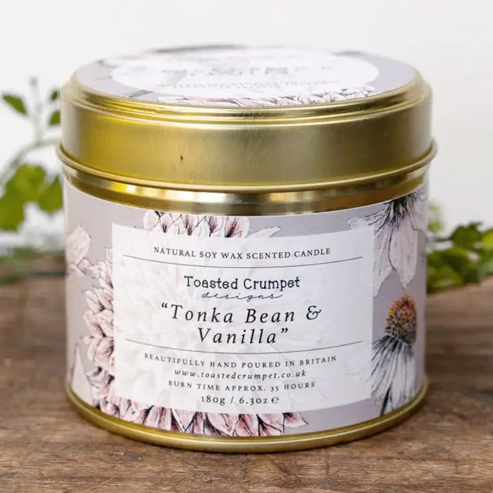 Candle in a tin with a floral label on a wooden surface
