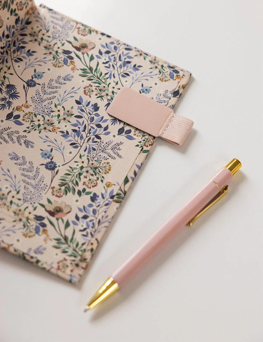 Floral notebook with a pink pen on a white background