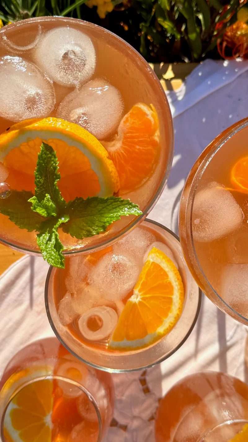 Cocktails with orange slices and ice cubes in clear glasses.