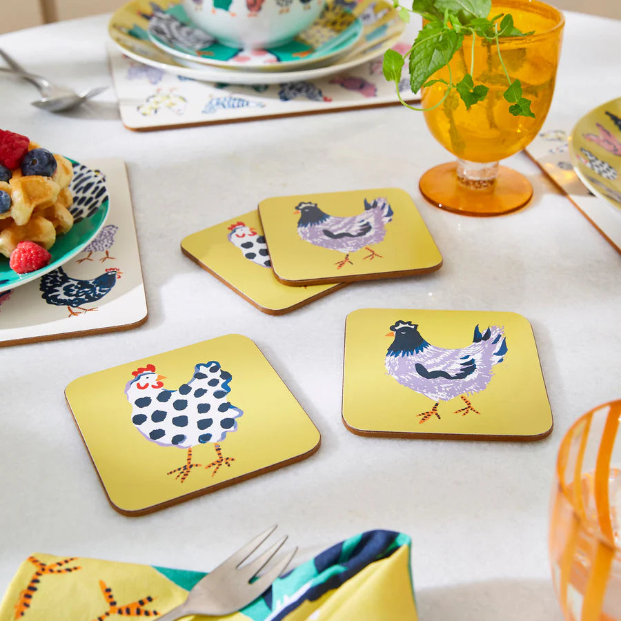 Yellow coasters with chicken designs on a table setting with waffles and berries.