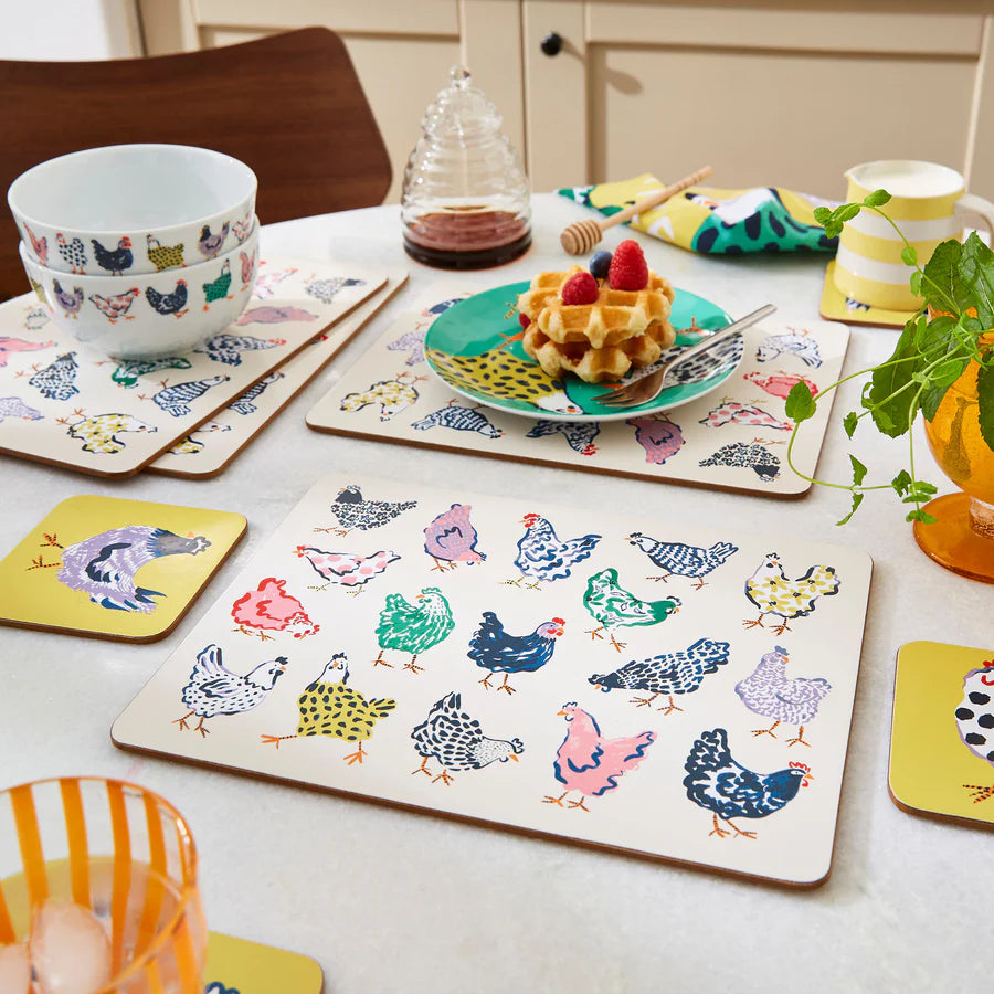 Table setting with colorful chicken-patterned placemats and coasters.