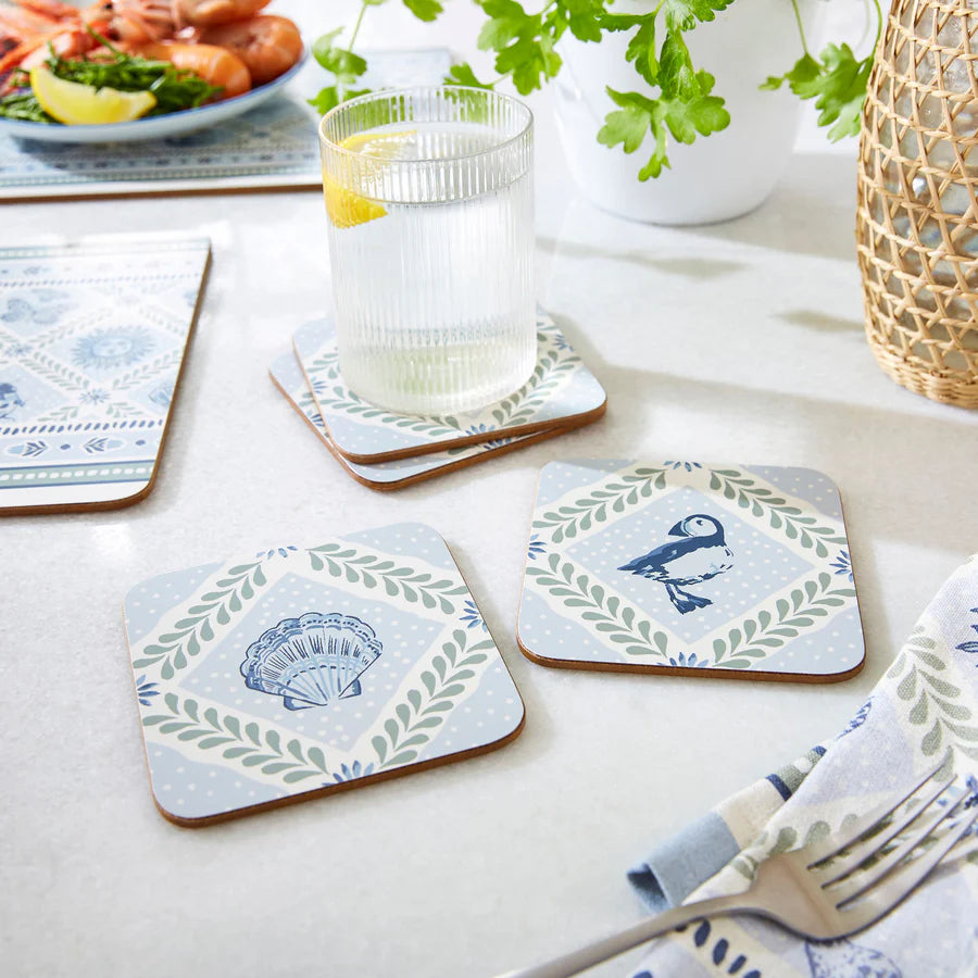 Set of coasters with decorative designs on a table with a glass of water and a plate of food.