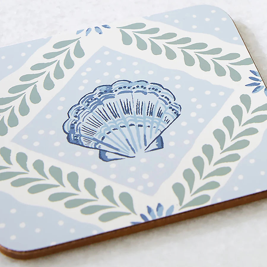 Decorative tile with a blue shell design on a light blue background with green leaves.