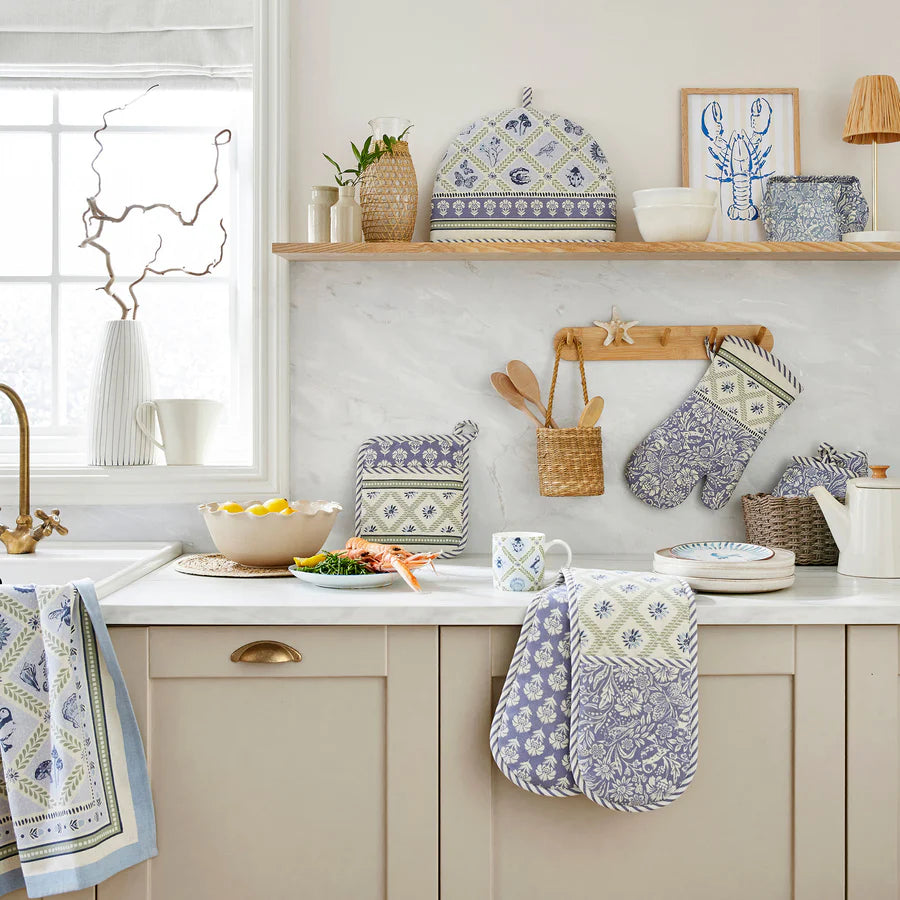 Kitchen with decorative towels, mugs, and kitchenware on a countertop.