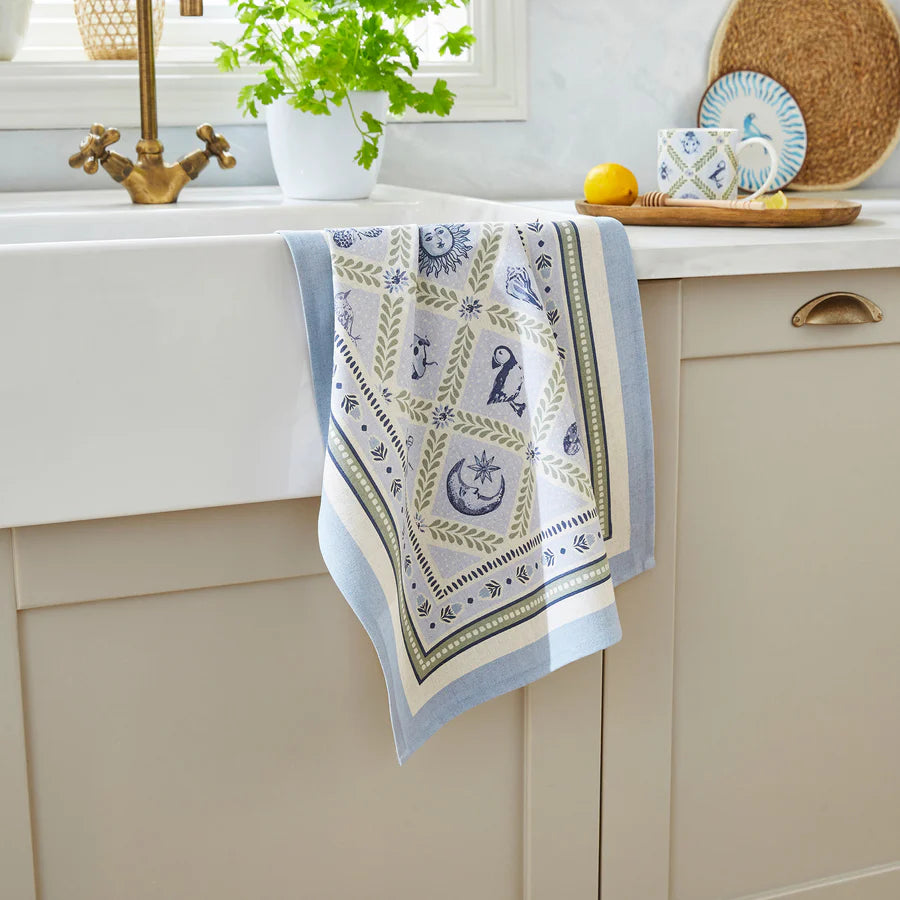 Decorative kitchen towel with celestial design hanging on a cabinet.