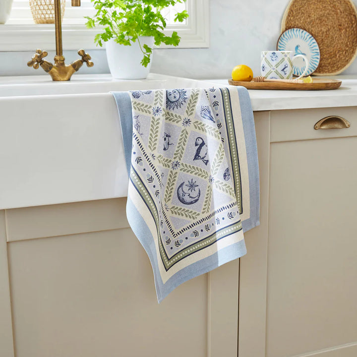 Decorative kitchen towel with celestial design hanging on a cabinet.