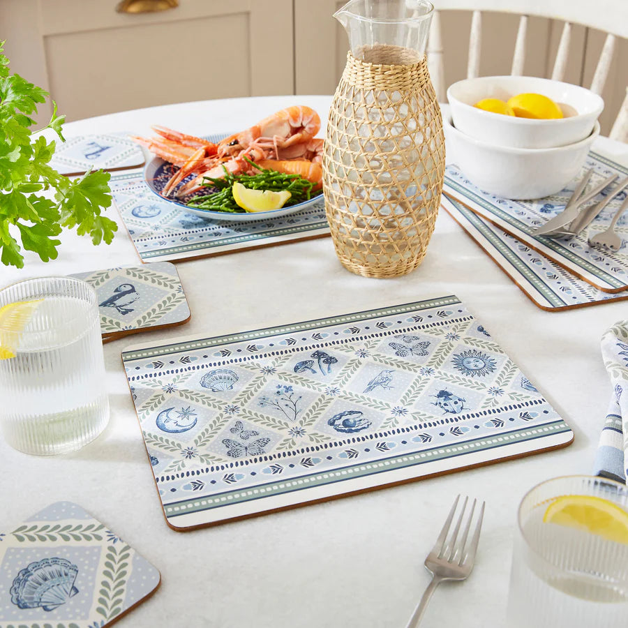Table setting with patterned placemats, plates, and a decorative vase.