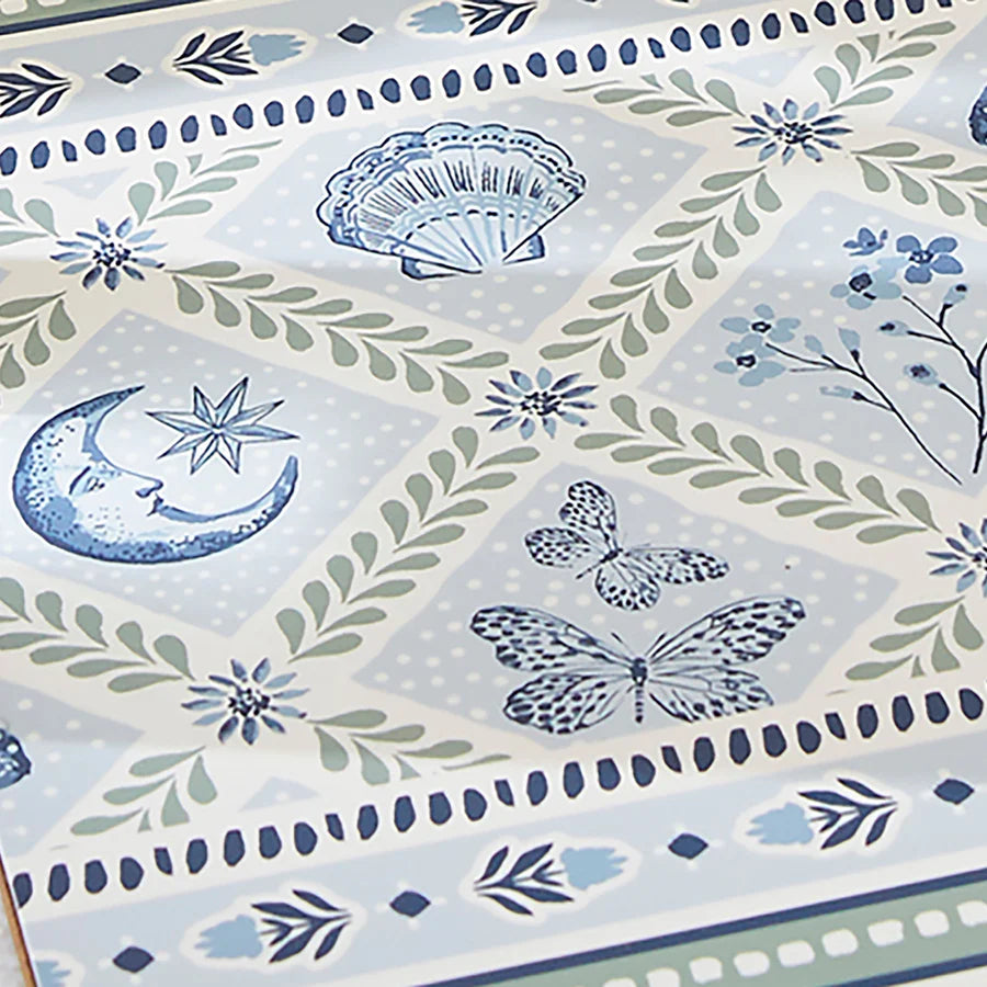 Decorative paper with blue and green floral, butterfly, and moon designs on a light blue background.