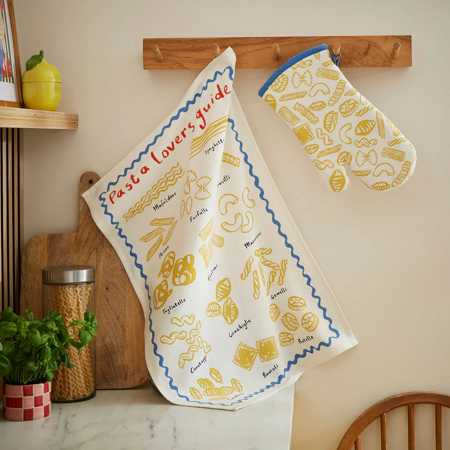 Cotton tea towel with pasta shapes on it hanging on a hook in a kitchen
