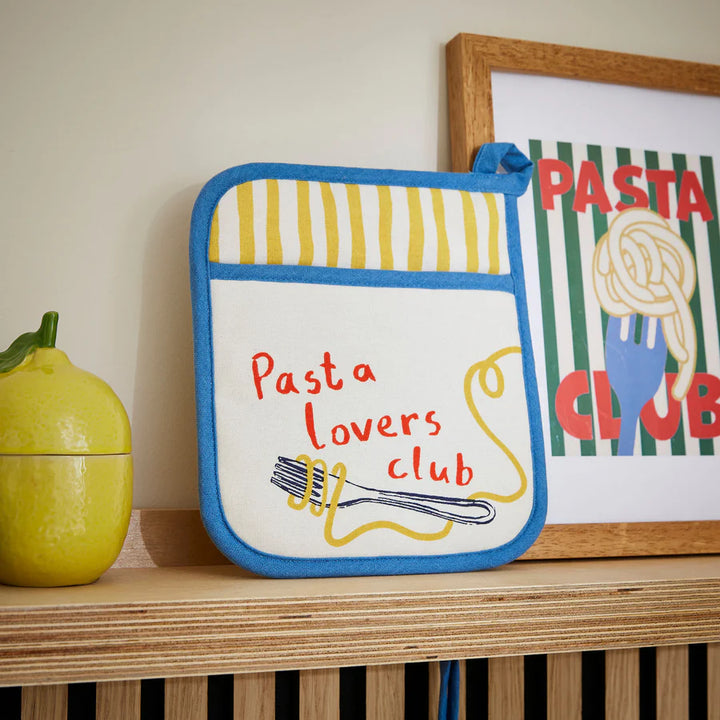 Potholder with 'Pasta Lovers Club' text on a shelf with decorative items.