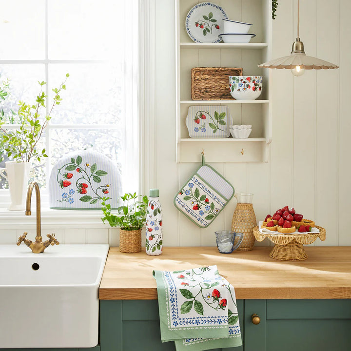 Kitchen with wooden countertop, green cabinets, and decorative items including a teapot, plates, and towels.