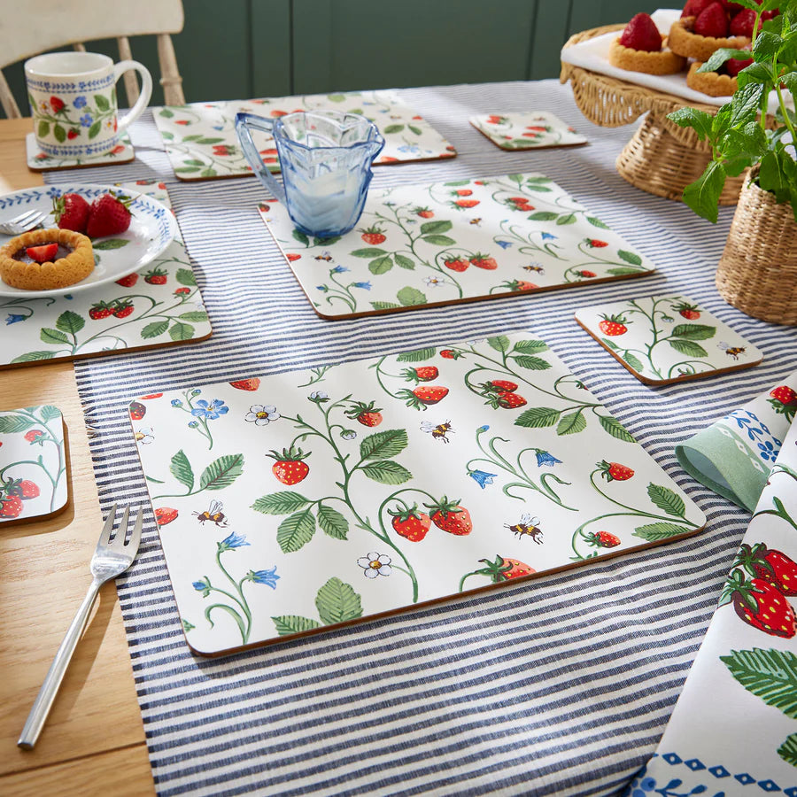 Table setting with strawberry-themed placemats and tablecloth.
