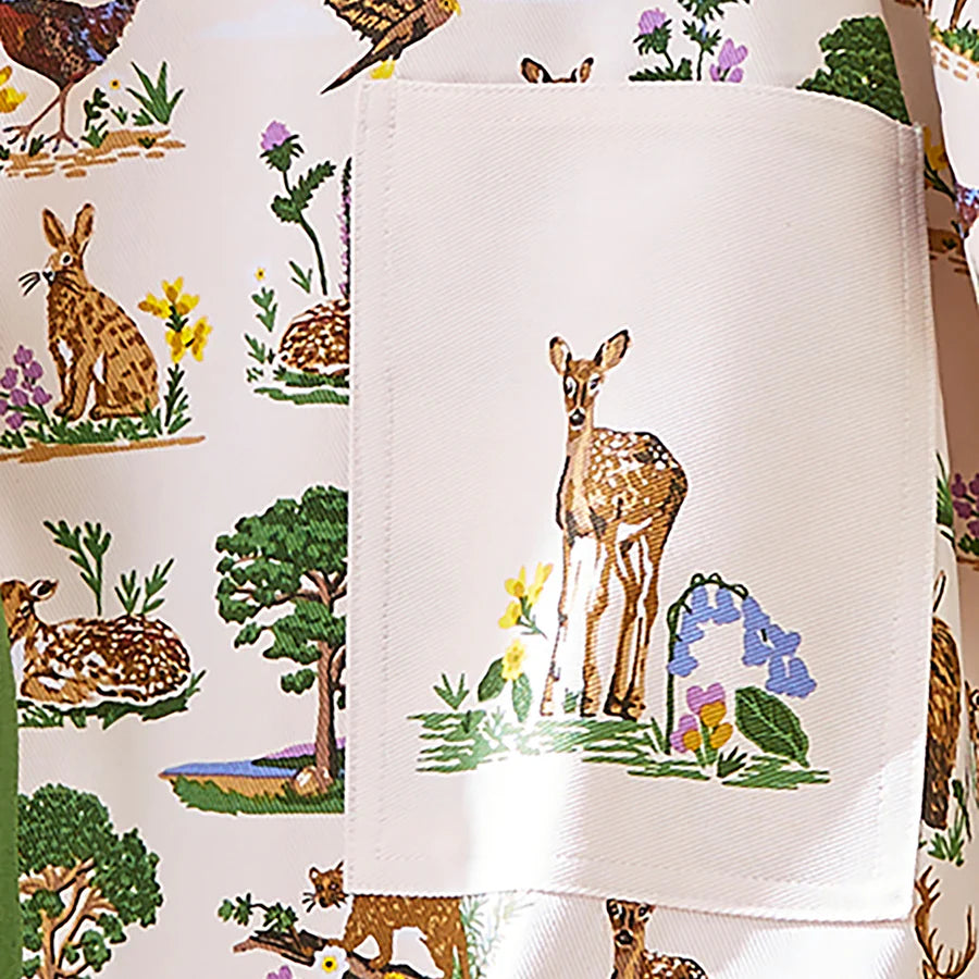Fabric with deer and nature-themed design, featuring a close-up of a white fabric with embroidered deer.