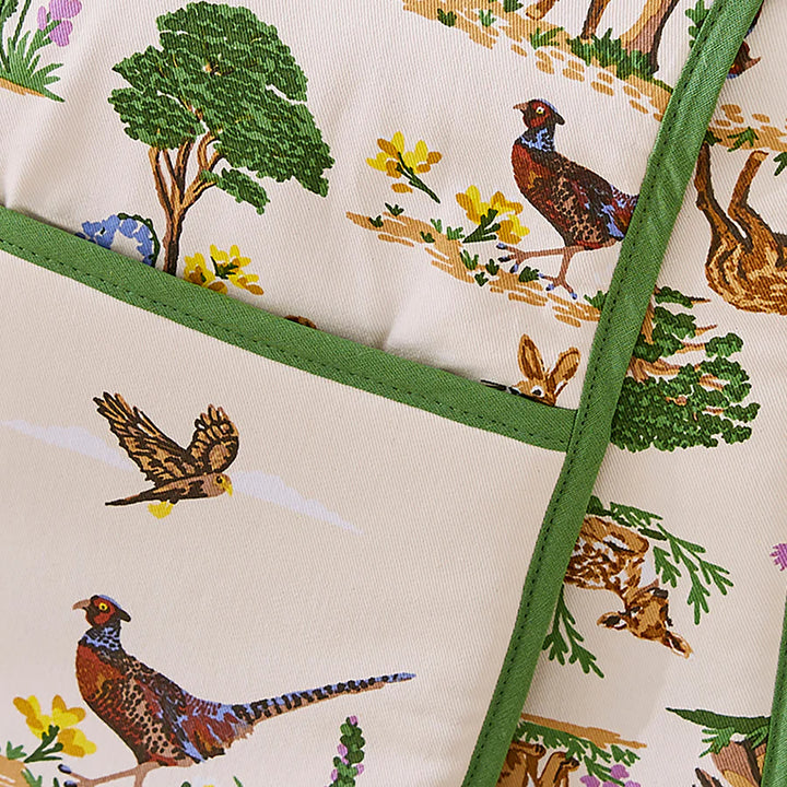 Close-up of a oven glove with bird and nature pattern, featuring green edge.