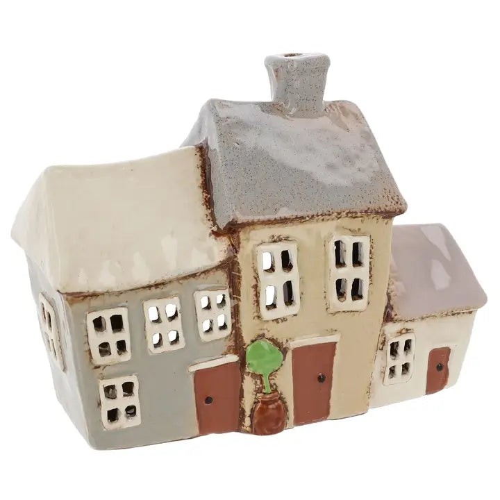 Ceramic house-shaped tealight holder with a white roof and various colored walls on a white background