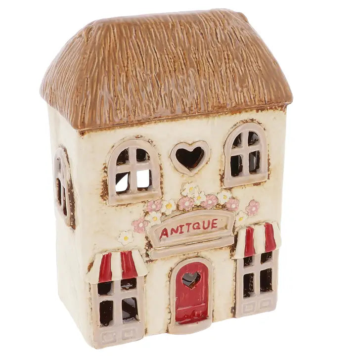 Decorative miniature house with a thatched roof and 'Antique' sign on a white background