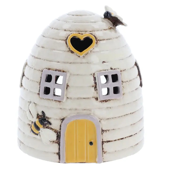 Decorative beehive  tealight holder  with a heart window and yellow door on a white background