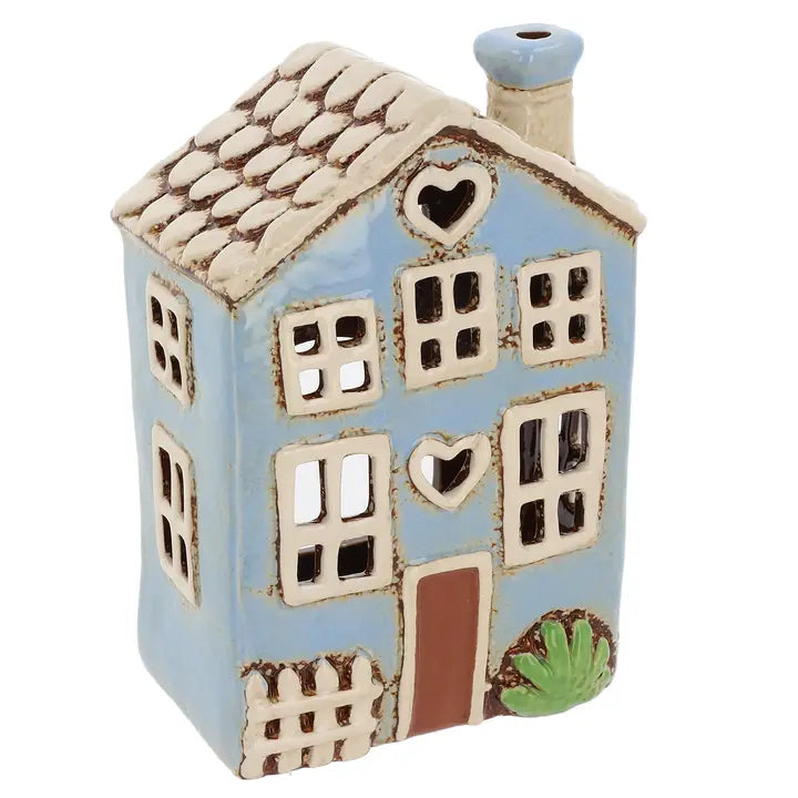 Ceramic house-shaped tealight holder with a light blue body, white roof, and brown door on a white background.