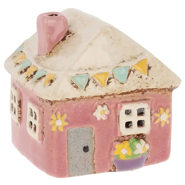 Ceramic house-shaped tealight holder with a pink roof and colorful decorations on a white background