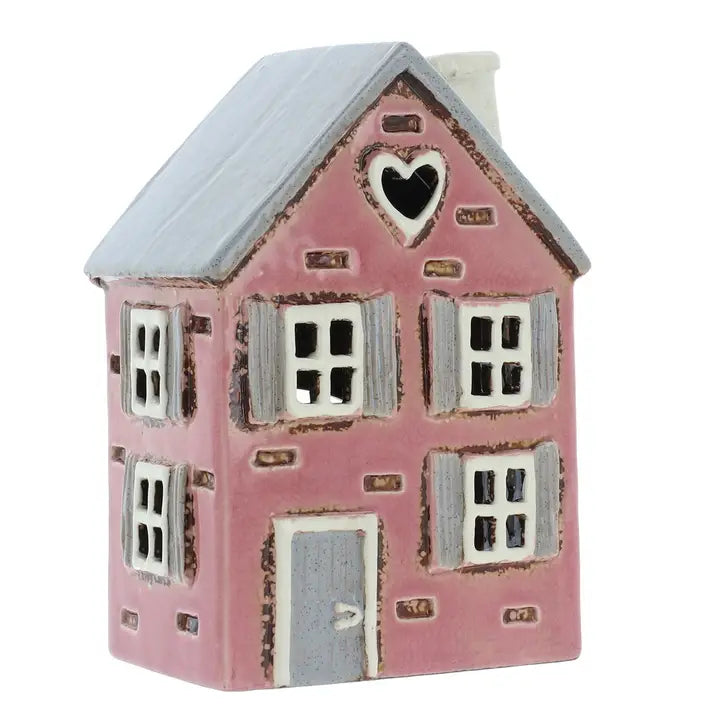 Pink ceramic house  tealight holder  with a heart window on a white background