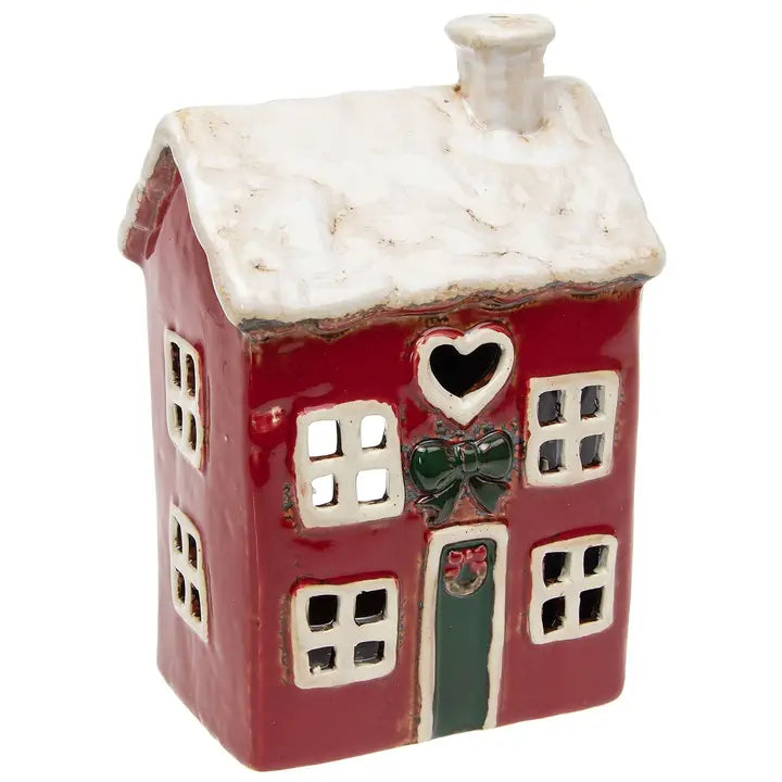 Decorative ceramic tealight house with red body, white roof, and green door on a white background
