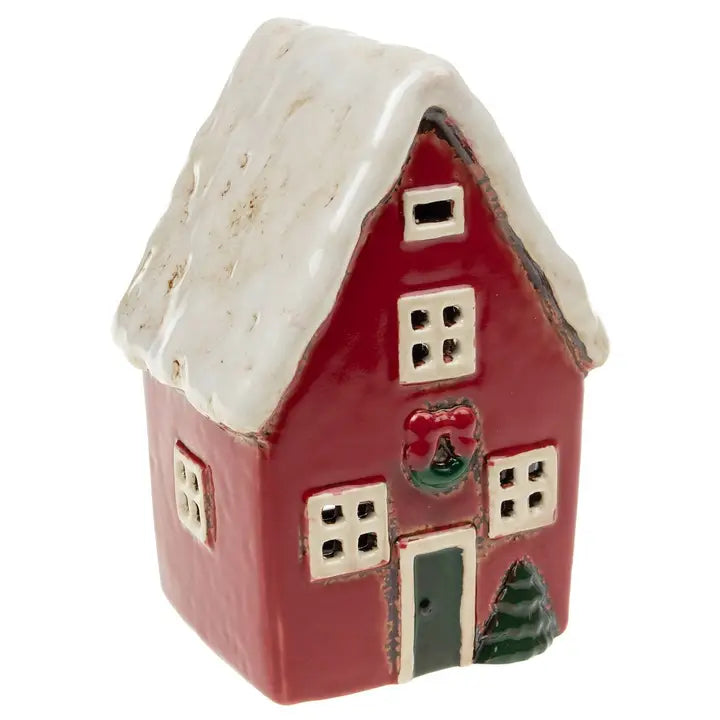Small ceramic tealight house with a red body, white roof, and decorative elements on a white background