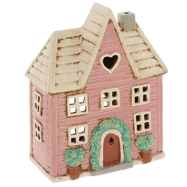 Pink ceramic house tealight holder with a heart window on a white background