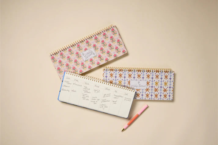 Three spiral-bound notebooks with floral and geometric patterns on a beige background