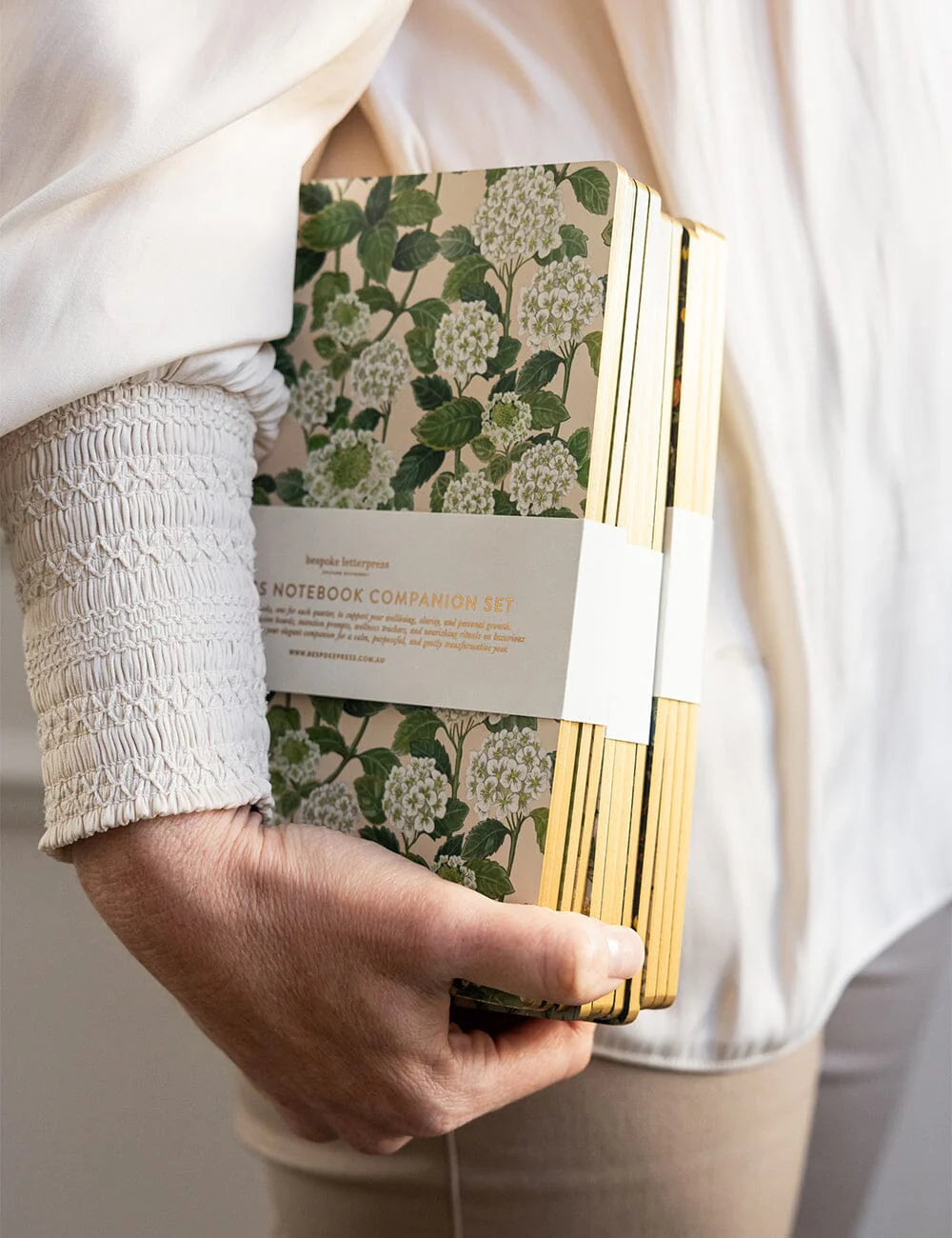 Hand holding a notebook with floral design and gold accents