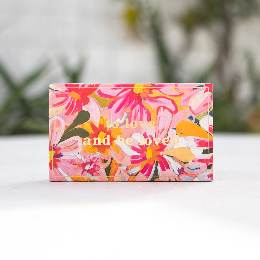 Floral patterned box with 'to love and be loved' text on a white surface