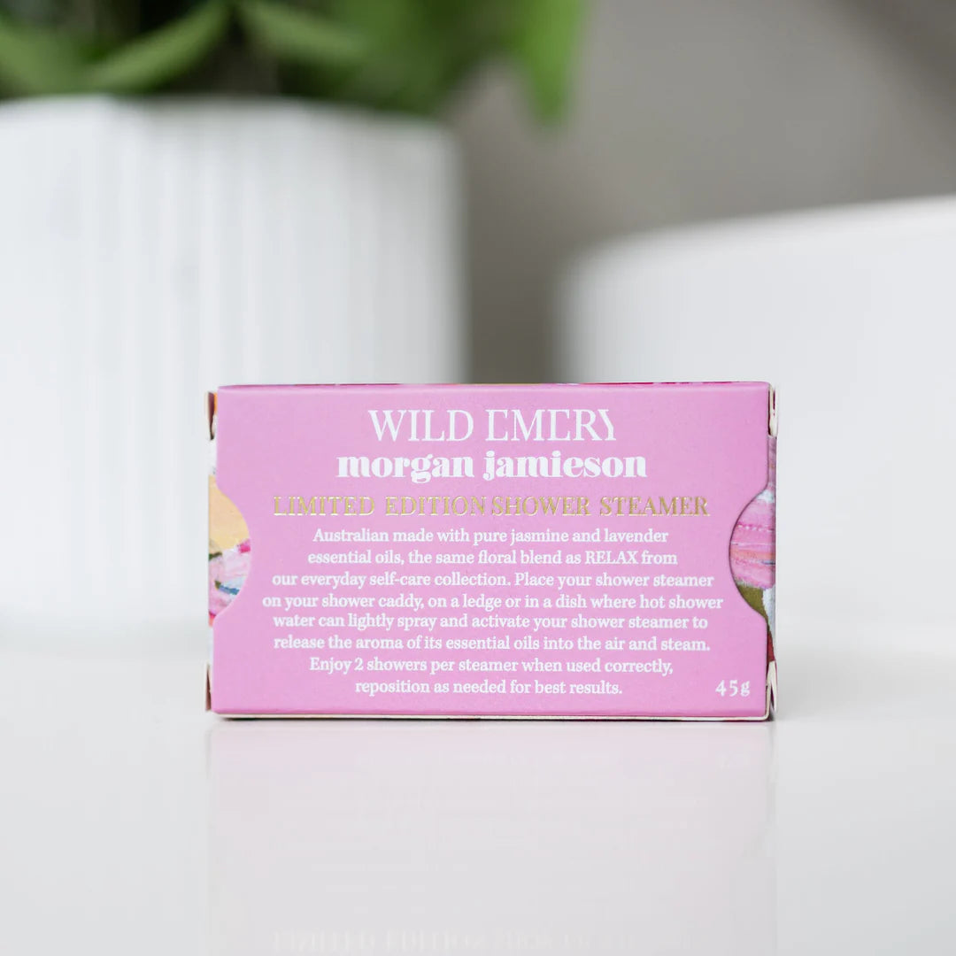 Pink packaging of Wild Emery morgan jamieson shower steamers on a white surface with a blurred background.