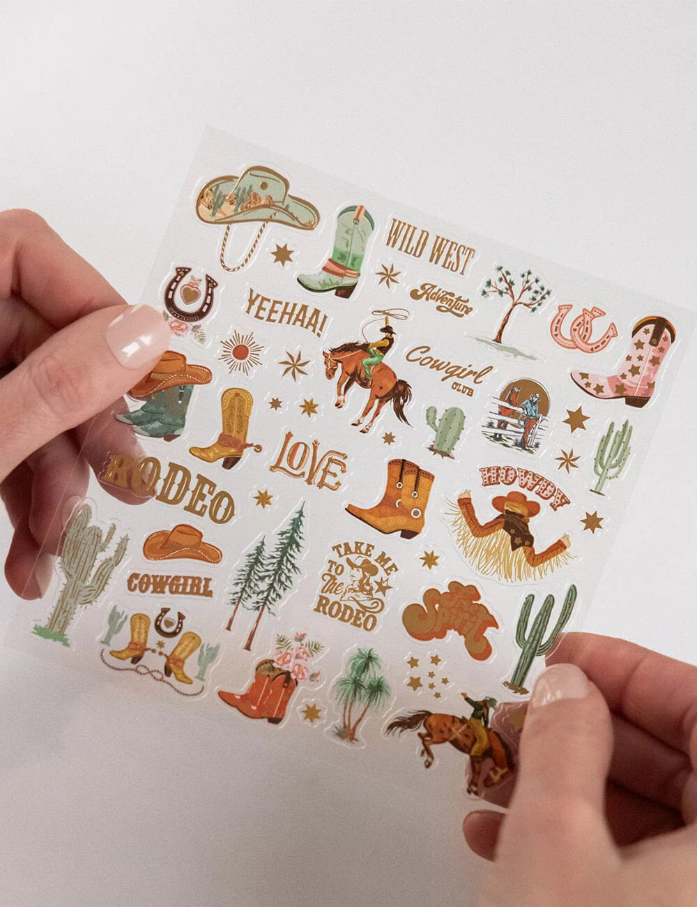 Sheet of western-themed stickers held by a person on a white background