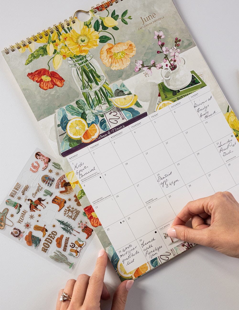 Floral-themed calendar with a hand holding it on a light background