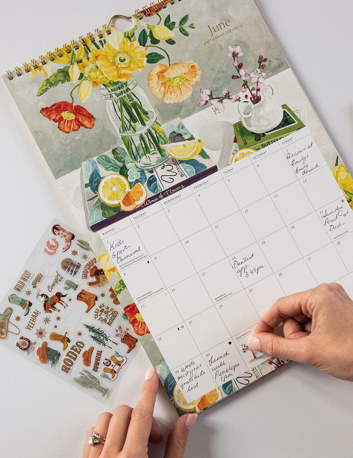 Floral-themed calendar with a hand holding it on a light background