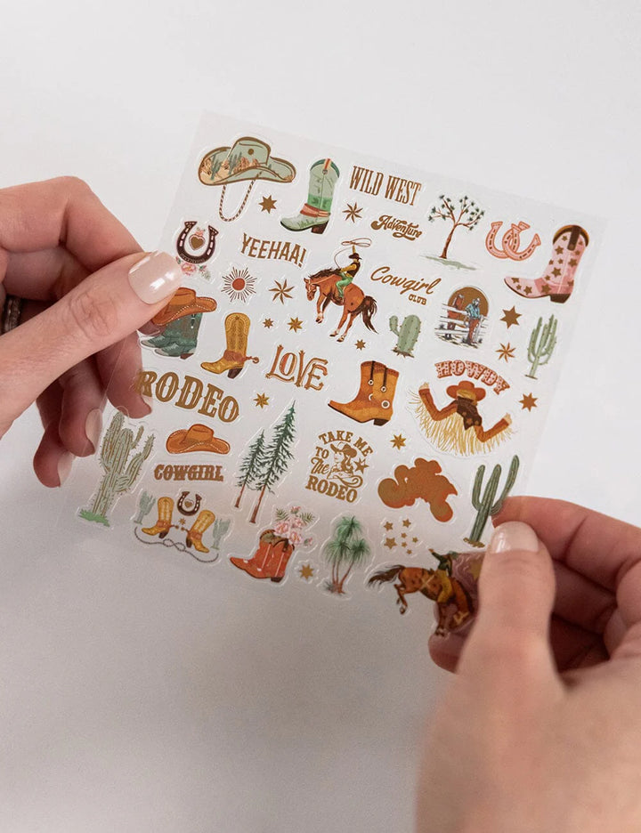 Sheet of western-themed stickers held by a person on a white background