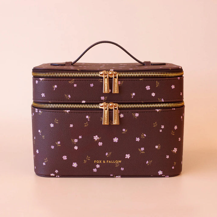 Makeup vanity case with floral pattern and gold zippers on a beige background